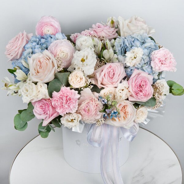 Blue/purple hydrangea - 2, Peony style roses - 3, Ranunculus Pink - 3, lisianthus - 3, Pink carnation - 7, Alstromeria white, soft pink - 11, Peony sprayrose - 2, Peony rose pink 'OHara' - 3, Round flower box medium, Oasis, Ozotamnus, Oksipetalum, Eucalyptus, Ribbon