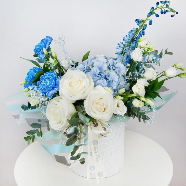 Blue/purple hydrangea - 3, Blue carnation - 5, White rose 50 cm - 5, lisianthus - 4, Colored gypsophila - 2, Round flower box small , Oasis, Wrapping Paper, Ruscus, Eucalyptus Cinerea, Blue Delphinium
