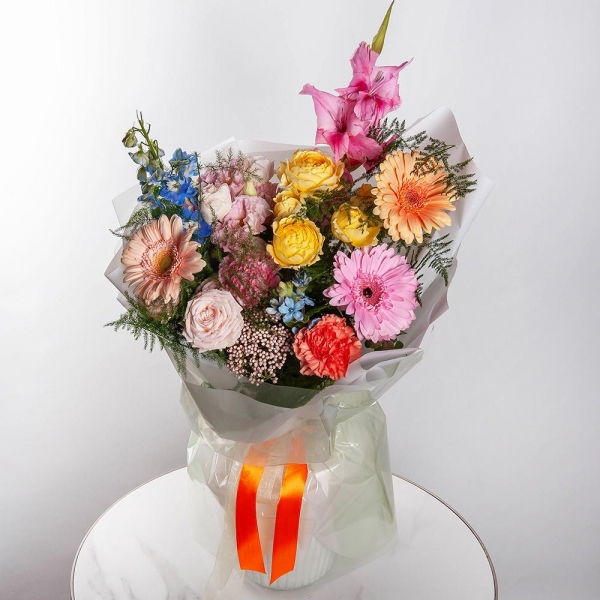 Gerbera daisies - 2, Pink Gladiolus - 1, Pink carnation - 3, Peony sprayrose - 1, Pink Lisianthus (Eustoma) - 1, Spray rose: yellow, orange 50 cm - 1, Gerbera pink - 2, Cream gerbera - 1, Blue Delphinium, Asparagus setaceus (1 pc.), Wrapping Paper