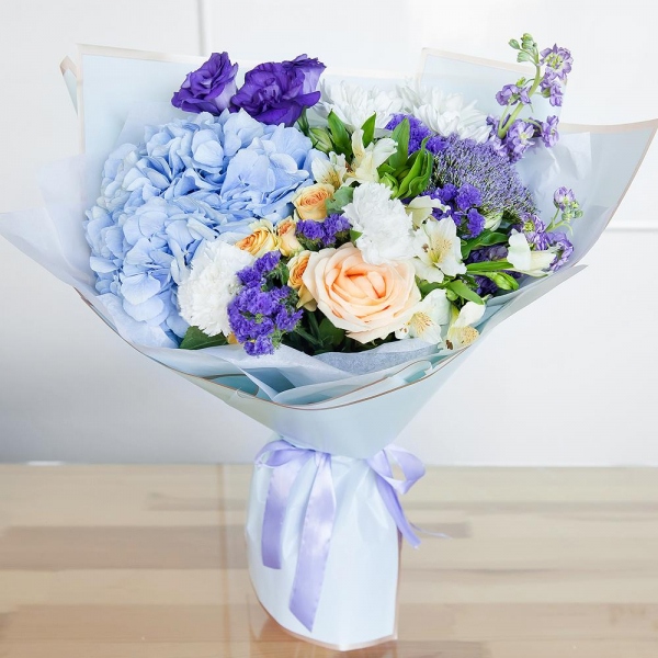 Matthiola Lilac - 2, Rose Cream 50 cm - 1, Carnation white, cream - 3, Spray rose: white, cream, light pink 50 cm - 2, Blue/purple hydrangea - 1, Alstromeria white, soft pink - 2, Baltica White Spray Chrysanthemum - 2, Purple Lisianthus (Eustoma) - 1, Trachelium, Blue Statice, Wrapping Paper