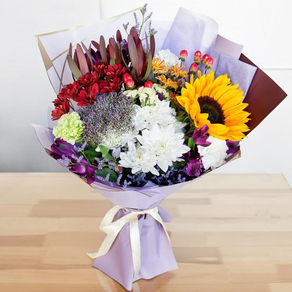 Green carnation - 2, Baltica White Spray Chrysanthemum - 1, Alstromeria lilac, purple - 4, Sunflower - 1, Bacardi Yellow Spray Chrysanthemum - 2, Bacardi Red Spray Chrysanthemum - 1, Carnation white, cream - 2, White statice, Hypericum, Limonium (1 pc.), Leukodendron, Wrapping Paper, Trachelium